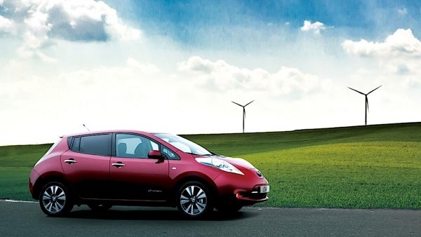 Nissan Leaf en color Coulis Red frente a turbinas de viento