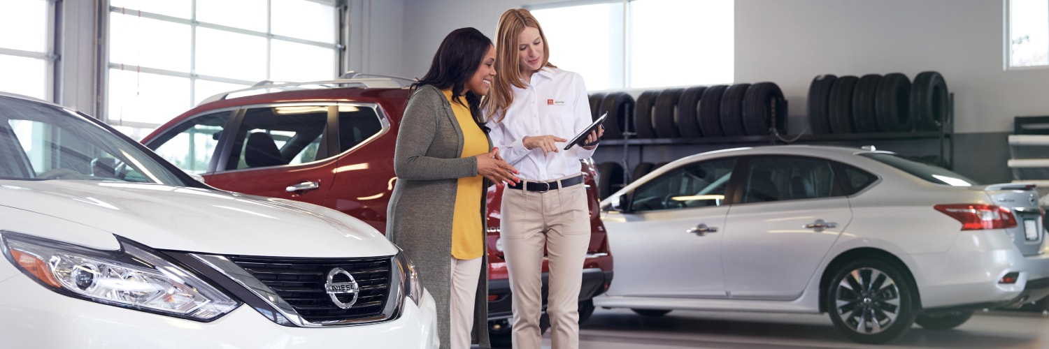 Dos mujeres exploran las ventajas de comprar vehículos usados certificados Nissan