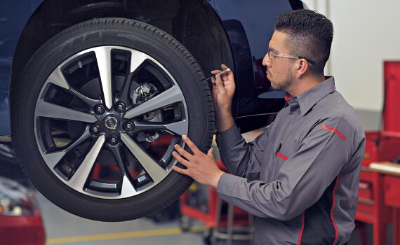 Técnico de Nissan inspeccionando un vehículo usado certificado con un plan de mantenimiento de 1 año