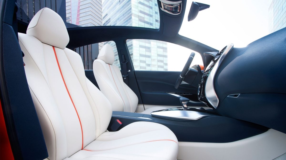 Nissan Invitation spacious front seats shown in white cloth with orange trim