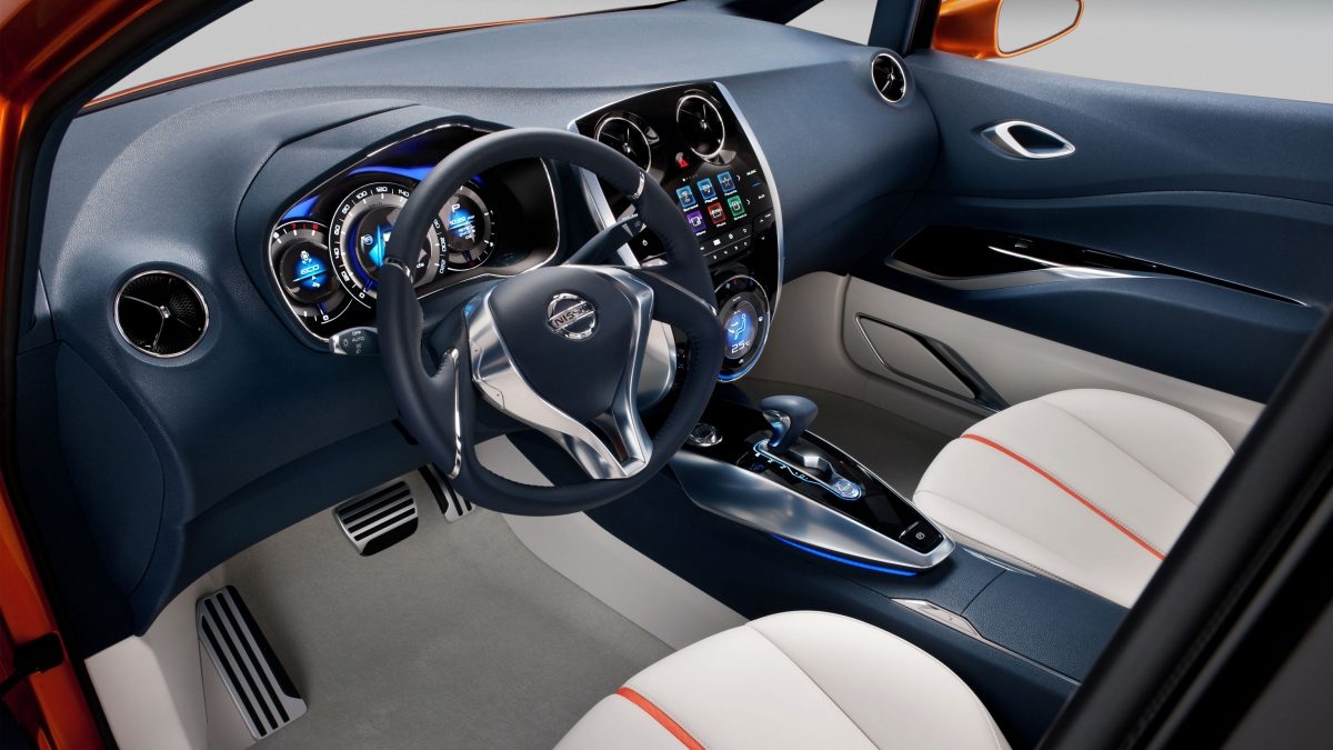 Nissan Invitation interior showing steering wheel, dashboard and white cloth seats with orange trim