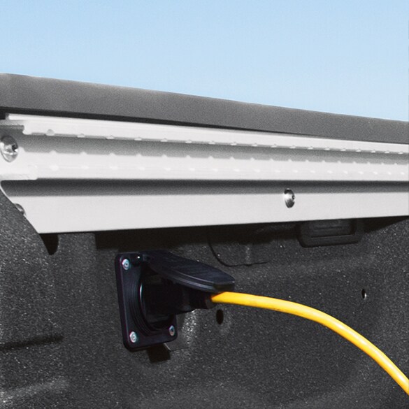 Se muestra un cable amarillo enchufado a un tomacorriente de 120 voltios en la caja de la Nissan Titan 2022 .