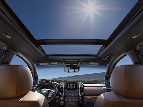 Vista desde el asiento trasero de la Nissan TITAN 2024 con doble techo corredizo panorámico en un día soleado
