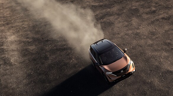 El Nissan Ariya 2023 visto desde arriba conduciendo por un planicie con polvo