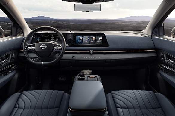 Vista amplia del asiento delantero, la doble pantalla y la consola central en el interior del Nissan Ariya 2023