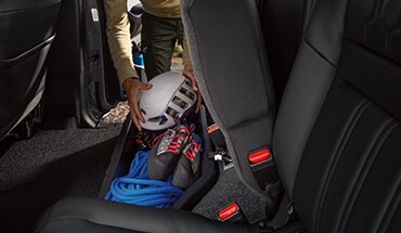 Asiento trasero de la Nissan Frontier 2022 levantado para mostrar el almacenamiento debajo del asiento con soga y equipos para escalar.