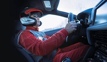 Imagen de un conductor de carreras con casco y tras el volante de un Nissan GT-R 2021