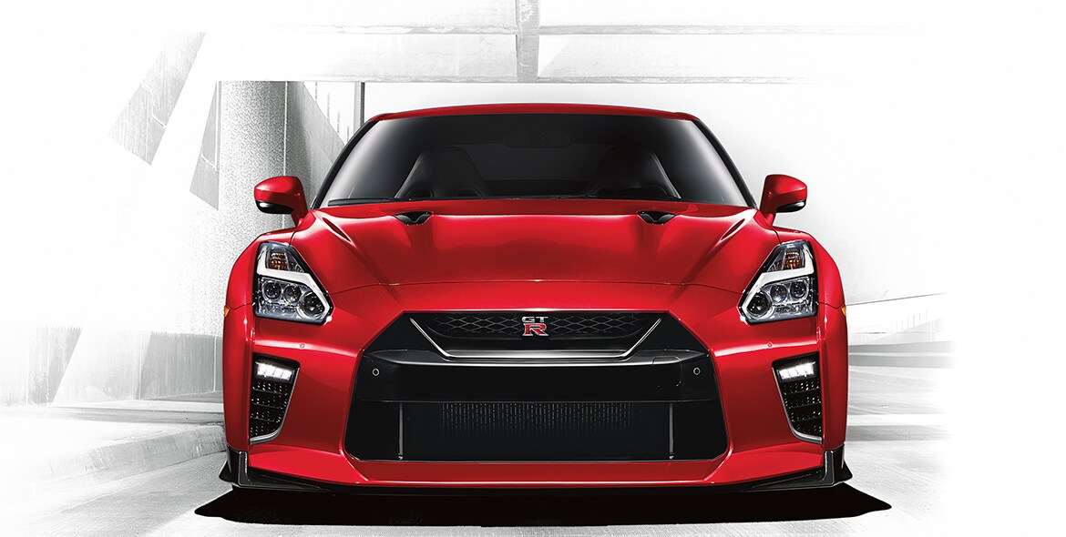 Vista de la fascia delantera del Nissan GT-R 2021 en color solid red al entrar de noche en un túnel