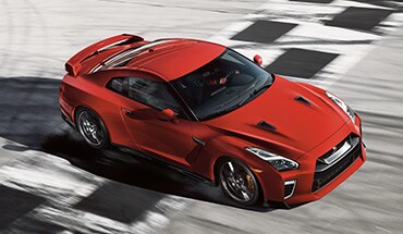 Nissan GT-R 2023 en color Solid Red cruza la línea de cuadros en la pista de carreras.