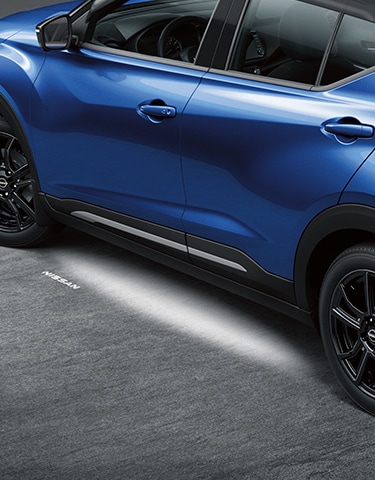El Nissan Kicks 2024 en color azul con iluminación exterior del piso encendida