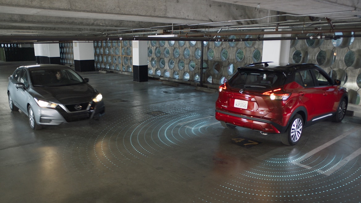 El Nissan Kicks 2024 saliendo de un estacionamiento con sensores de protección que detectan un auto detrás