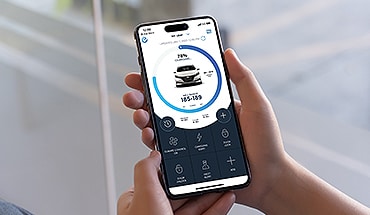 Teléfono inteligente abierto con nivel de carga en la pantalla del Nissan LEAF 2024