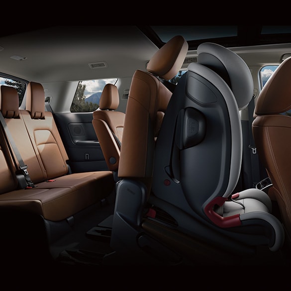 Vista interior del Nissan Pathfinder 2024 en la que se ve un asiento infantil vacío sujeto a un asiento de la 2ª fila, que está inclinado hacia delante.