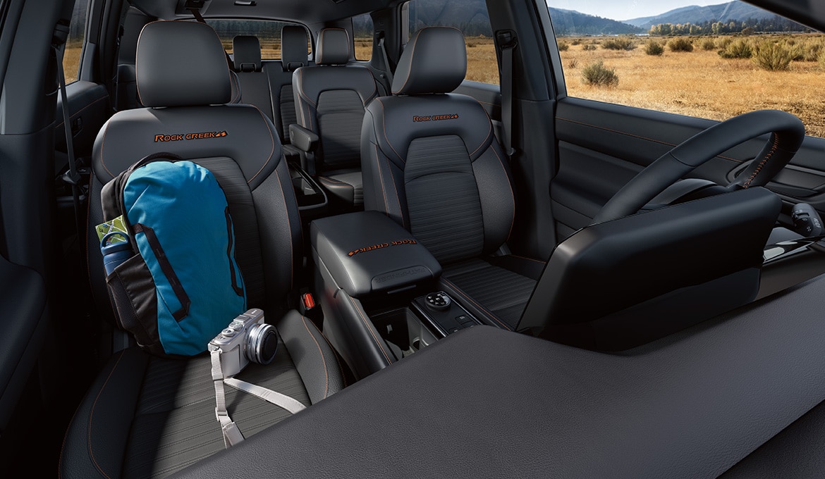 Vista interior del Nissan Pathfinder 2024 con mochila y cámara en el asiento del acompañante.