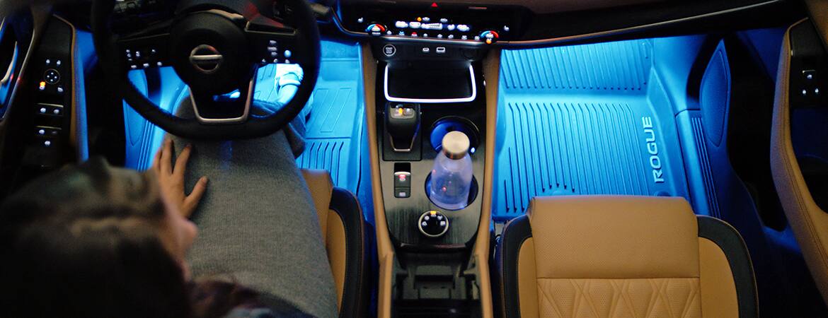 Nissan Rogue 2023 mostrando la iluminación de acento azul del interior en el espacio para los pies.