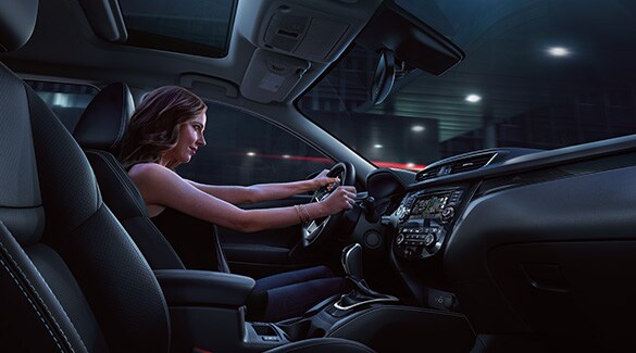 Imagen del Nissan Rogue Sport 2022 en la que se ve al conductor desde el asiento del pasajero de noche utilizando la dirección deportiva