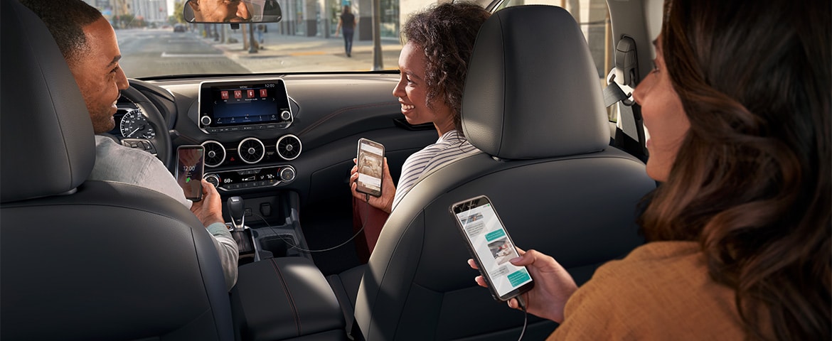 Interior del Nissan Sentra 2024 con personas utilizando sus teléfonos inteligentes para mostrar la conectividad para los dispositivos.