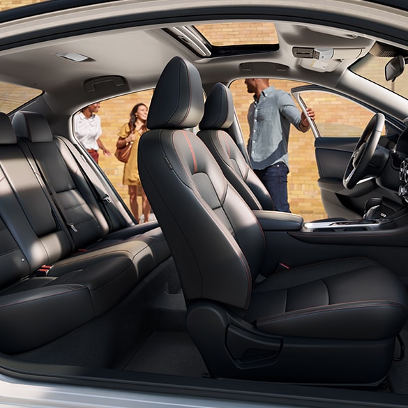 El Nissan Sentra 2024 visto desde el lado del pasajero; las puertas delanteras y traseras del lado del conductor están abiertas y se ve el espacioso interior.