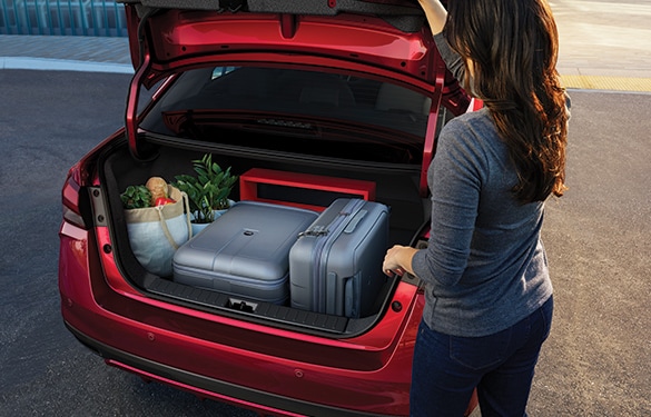 Se muestra una persona cerrando la cajuela del Nissan Versa 2023 con el equipaje y la compra dentro.