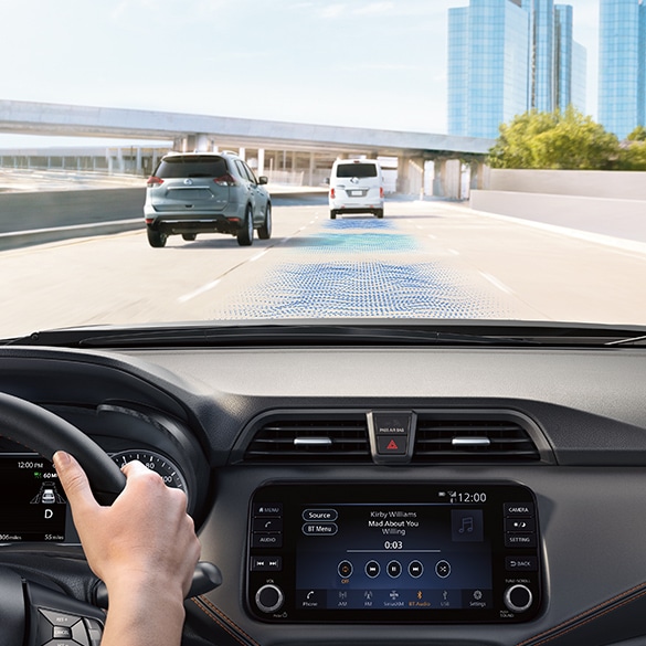 Nissan Versa 2024 circulando por una autopista urbana, muestra los sensores de control inteligente de crucero