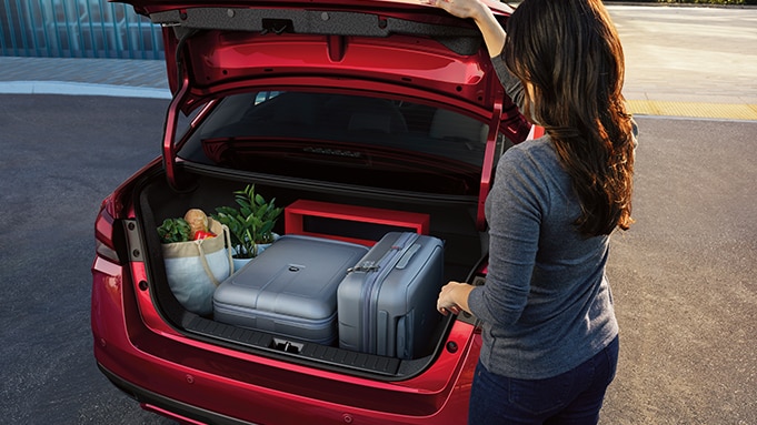 Vista trasera del Nissan Versa 2024 con el maletero abierto y el equipaje y la compra en su interior